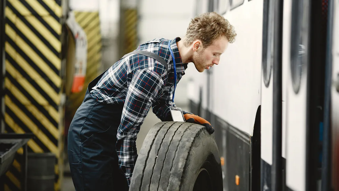 man lyfter däck för att sätta på lastbilen